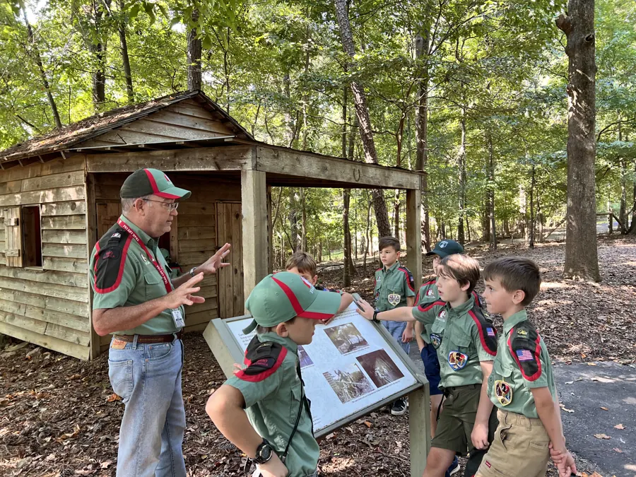 A leader teaching Trailmen beside a historic farm building at McDaniel Farm Park