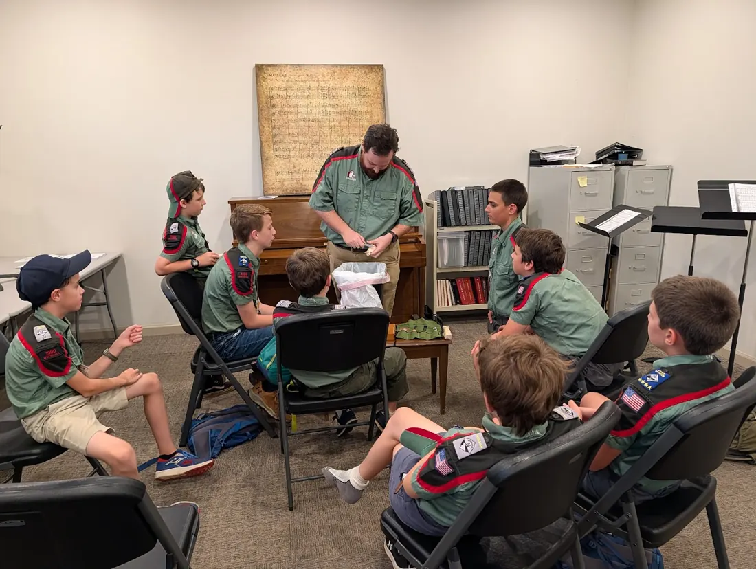 A troop mentor demonstrating wood carving to Trailmen at a meeting